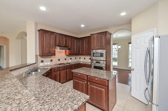 kitchen featuring kitchen peninsula, stainless steel appliances, sink, light tile patterned floors, and a chandelier