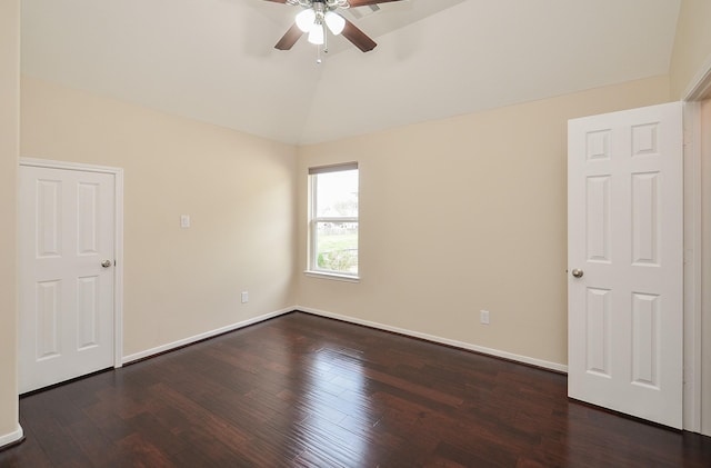 spare room featuring lofted ceiling, dark wood-style flooring, a ceiling fan, and baseboards