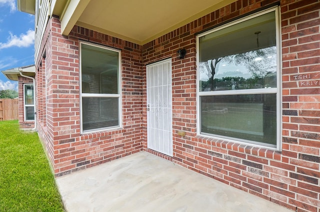 doorway to property with a patio area and brick siding