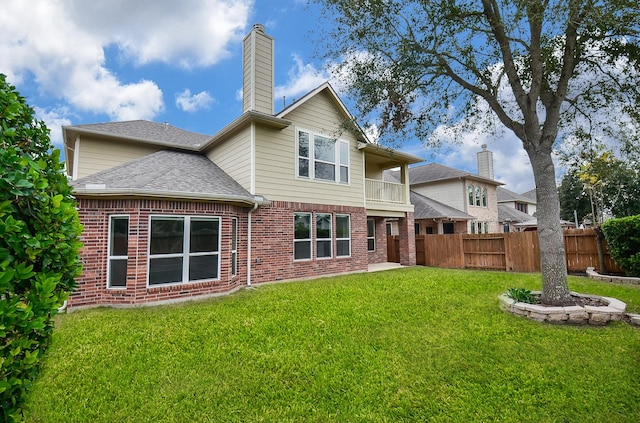 rear view of house with a balcony, a shingled roof, fence, and brick siding