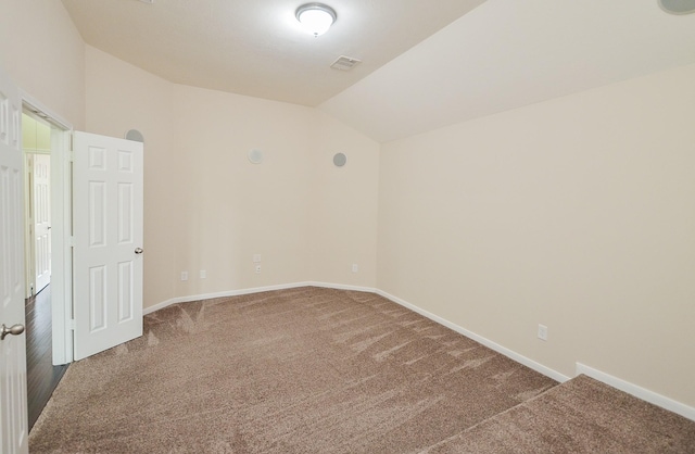 spare room featuring vaulted ceiling, carpet, visible vents, and baseboards