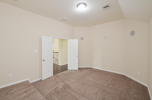 carpeted empty room featuring lofted ceiling, visible vents, and baseboards