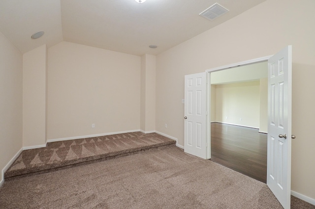 unfurnished room with dark colored carpet and lofted ceiling