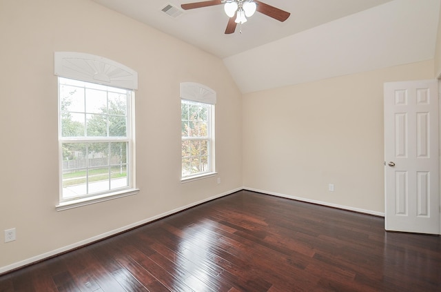 empty room with lofted ceiling, ceiling fan, visible vents, baseboards, and dark wood finished floors