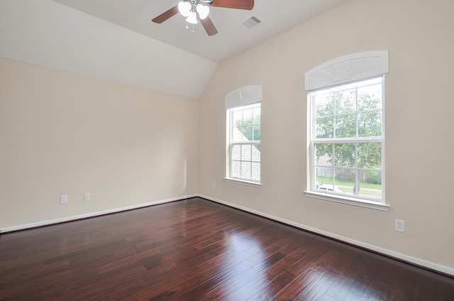 spare room featuring a wealth of natural light, ceiling fan, dark wood-type flooring, and vaulted ceiling