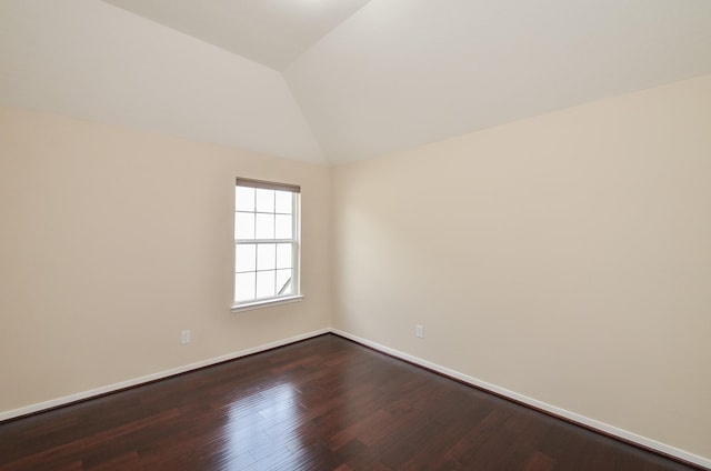 spare room featuring wood-type flooring and vaulted ceiling