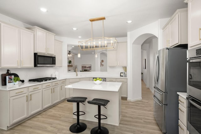 kitchen featuring sink, appliances with stainless steel finishes, decorative light fixtures, a kitchen island, and a breakfast bar area