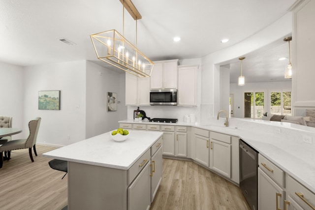 kitchen featuring kitchen peninsula, stainless steel appliances, sink, pendant lighting, and light hardwood / wood-style flooring