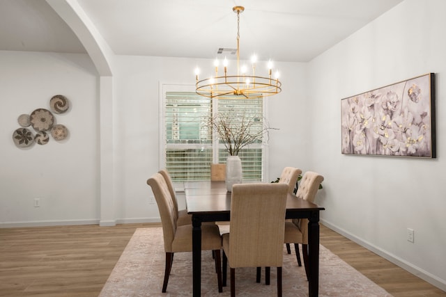 dining area with light hardwood / wood-style floors and a chandelier