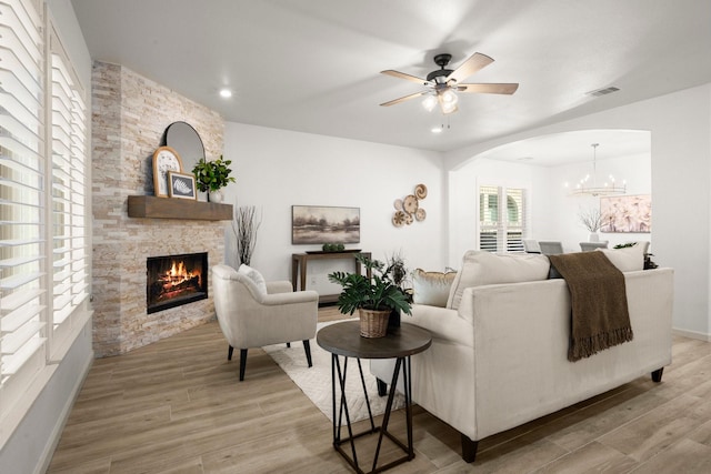 living room with a fireplace, ceiling fan with notable chandelier, and hardwood / wood-style flooring