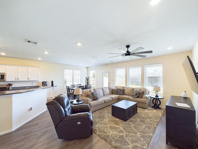 living room featuring a textured ceiling, dark hardwood / wood-style floors, and ceiling fan