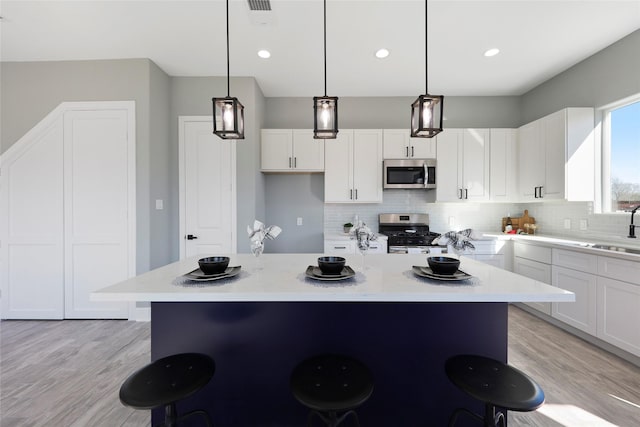 kitchen with sink, white cabinets, pendant lighting, and appliances with stainless steel finishes