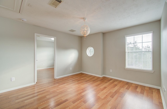 unfurnished room with a textured ceiling and light hardwood / wood-style floors