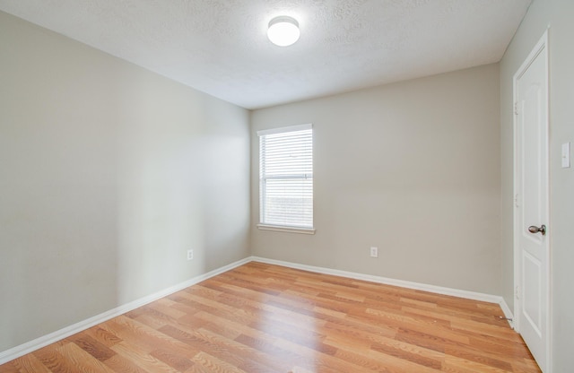 unfurnished room featuring a textured ceiling and light hardwood / wood-style flooring