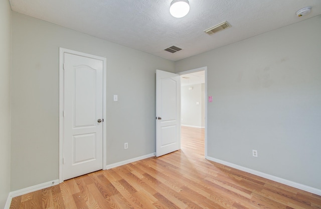 unfurnished room with a textured ceiling and light hardwood / wood-style flooring