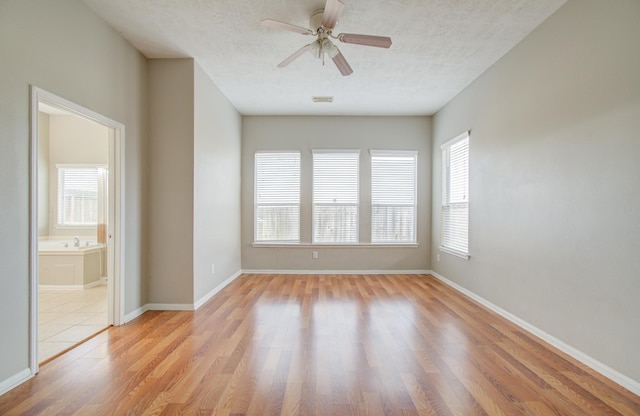 empty room featuring ceiling fan, light hardwood / wood-style floors, and a textured ceiling