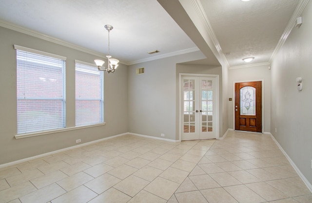 foyer with french doors, a healthy amount of sunlight, an inviting chandelier, light tile patterned floors, and ornamental molding