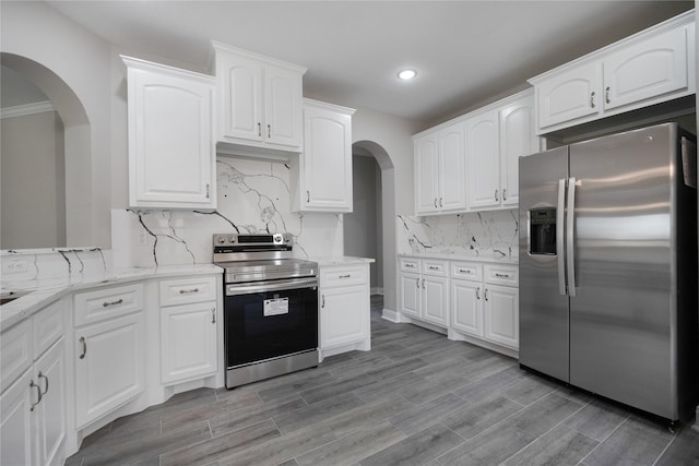 kitchen featuring decorative backsplash, appliances with stainless steel finishes, white cabinetry, and light stone counters