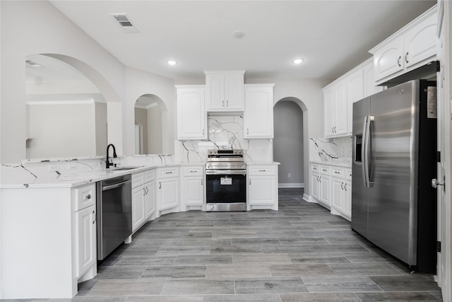 kitchen with white cabinetry, sink, light stone counters, decorative backsplash, and appliances with stainless steel finishes