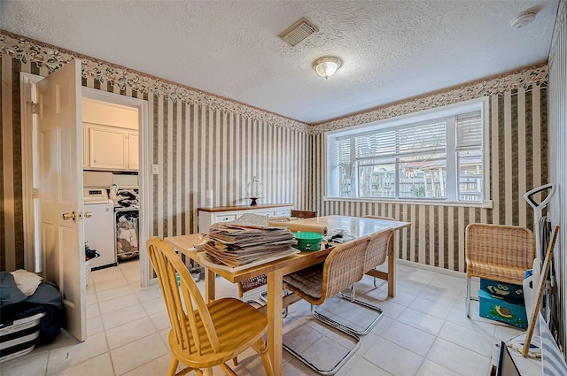 dining area featuring light tile patterned floors, a textured ceiling, and washer / dryer