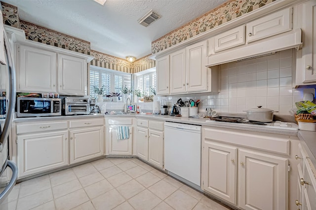 kitchen featuring backsplash, light tile patterned floors, white cabinets, and white appliances