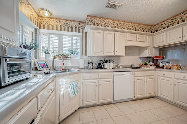 kitchen featuring white dishwasher, sink, white cabinetry, and a textured ceiling