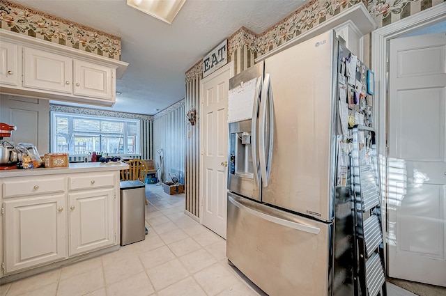 kitchen with stainless steel fridge with ice dispenser, light tile patterned floors, and white cabinetry