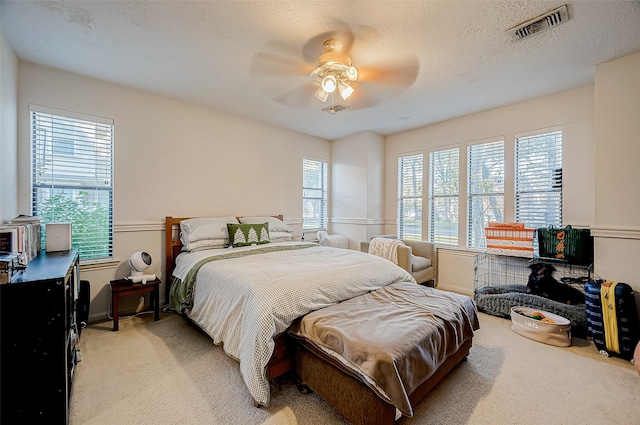 bedroom with a textured ceiling, light colored carpet, and ceiling fan