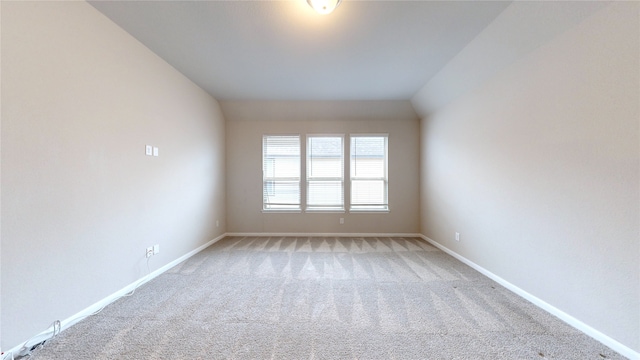 carpeted empty room featuring vaulted ceiling