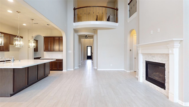 kitchen featuring dark brown cabinetry, sink, hanging light fixtures, and light hardwood / wood-style flooring