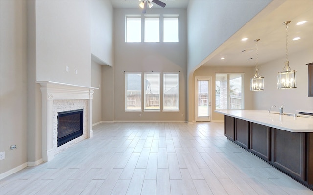 interior space with an island with sink, hanging light fixtures, a high ceiling, ceiling fan, and dark brown cabinetry