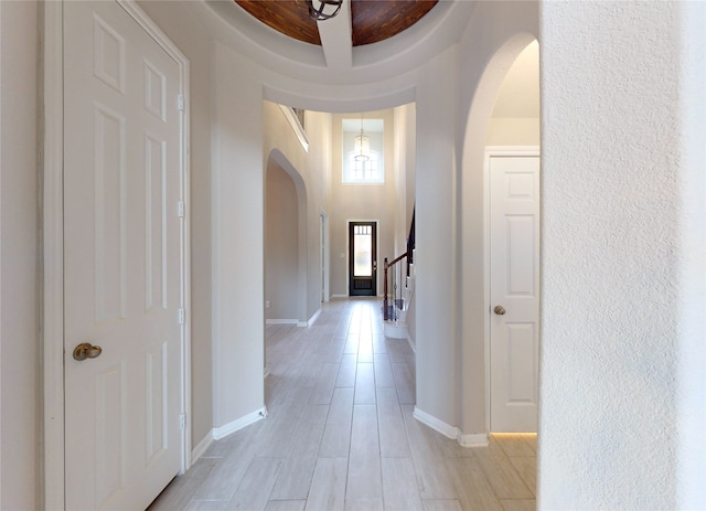 corridor featuring coffered ceiling, light hardwood / wood-style floors, and a high ceiling