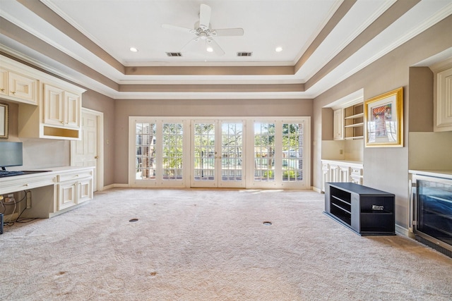 unfurnished living room featuring a raised ceiling, light colored carpet, and crown molding