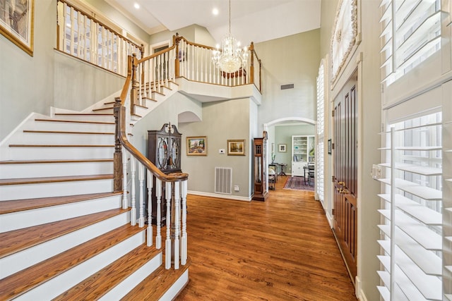 entryway featuring wood-type flooring, a high ceiling, and a notable chandelier