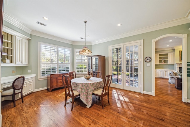 dining area with french doors, dark wood-type flooring, ornamental molding, and a notable chandelier