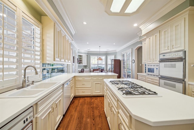 kitchen with sink, hanging light fixtures, kitchen peninsula, crown molding, and white appliances