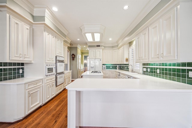 kitchen featuring kitchen peninsula, white cabinetry, sink, and white appliances