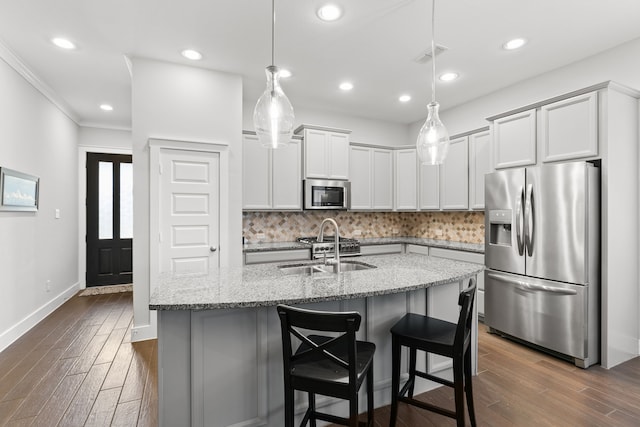 kitchen featuring sink, stainless steel appliances, tasteful backsplash, light stone counters, and decorative light fixtures