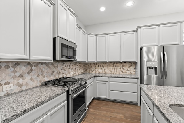 kitchen with white cabinetry, decorative backsplash, light stone counters, and appliances with stainless steel finishes