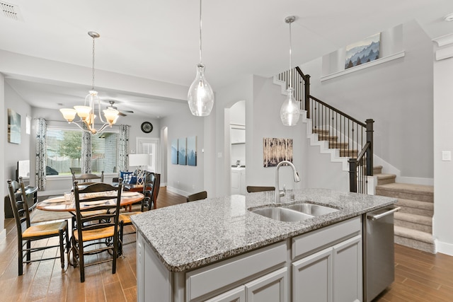 kitchen with pendant lighting, light wood-type flooring, a kitchen island with sink, and sink