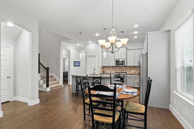 dining area with plenty of natural light, dark hardwood / wood-style flooring, and an inviting chandelier