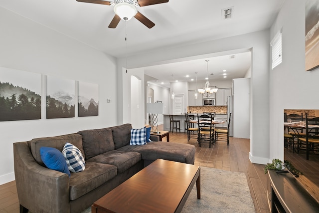 living room with hardwood / wood-style floors and ceiling fan with notable chandelier