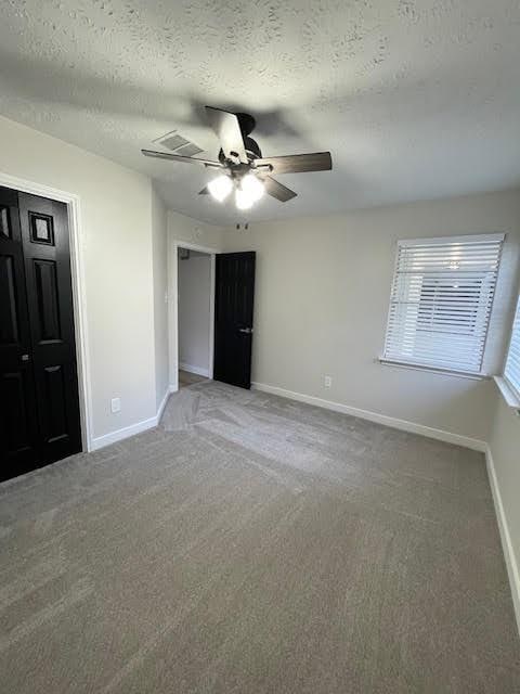 unfurnished bedroom with carpet, ceiling fan, and a textured ceiling