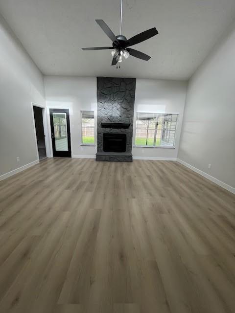 unfurnished living room featuring ceiling fan, a fireplace, and light wood-type flooring