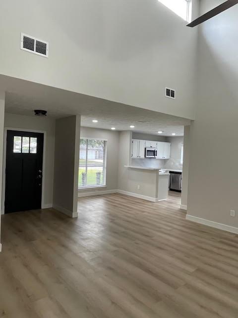 unfurnished living room featuring light hardwood / wood-style floors and a high ceiling