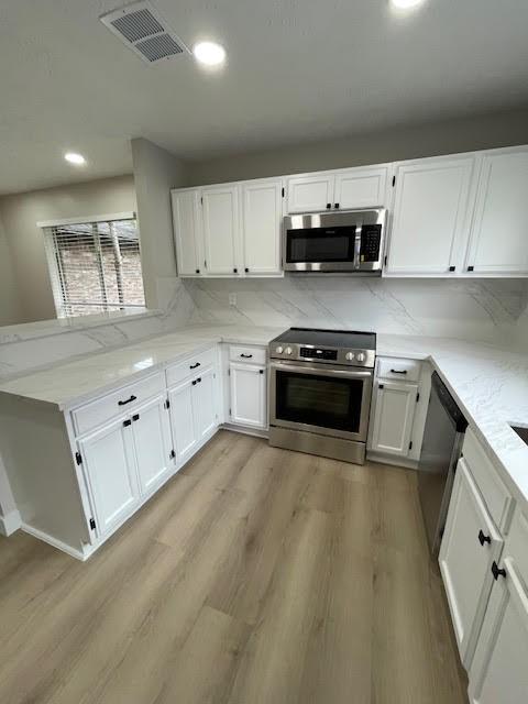 kitchen with white cabinetry, appliances with stainless steel finishes, and tasteful backsplash