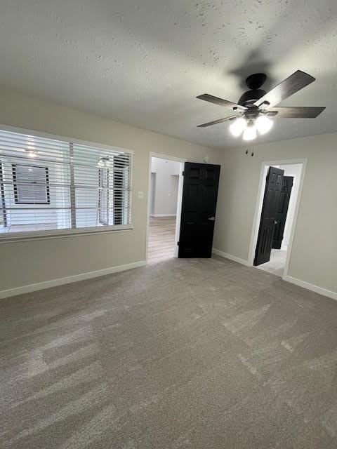 empty room featuring carpet flooring, ceiling fan, and a textured ceiling