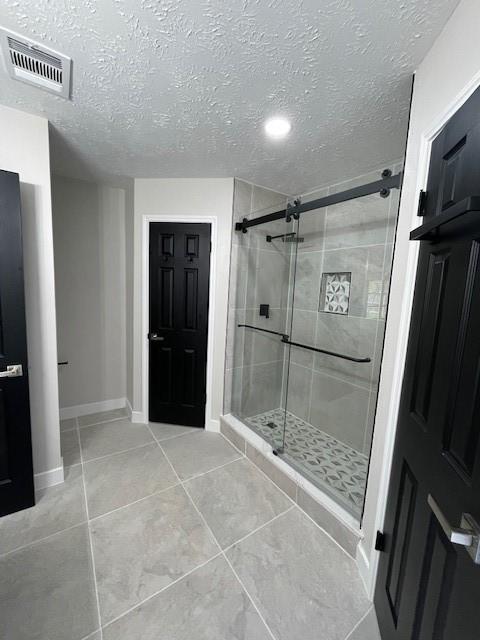 bathroom featuring tile patterned flooring, a textured ceiling, and an enclosed shower