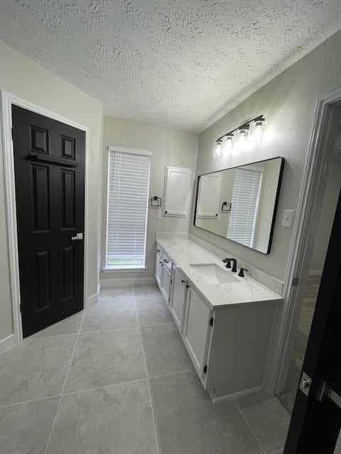 bathroom featuring tile patterned flooring, vanity, and a textured ceiling