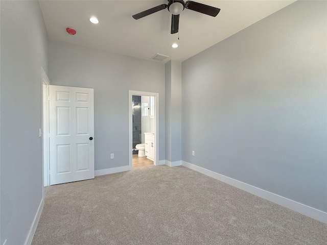 unfurnished bedroom with light carpet, ceiling fan, a high ceiling, and ensuite bath